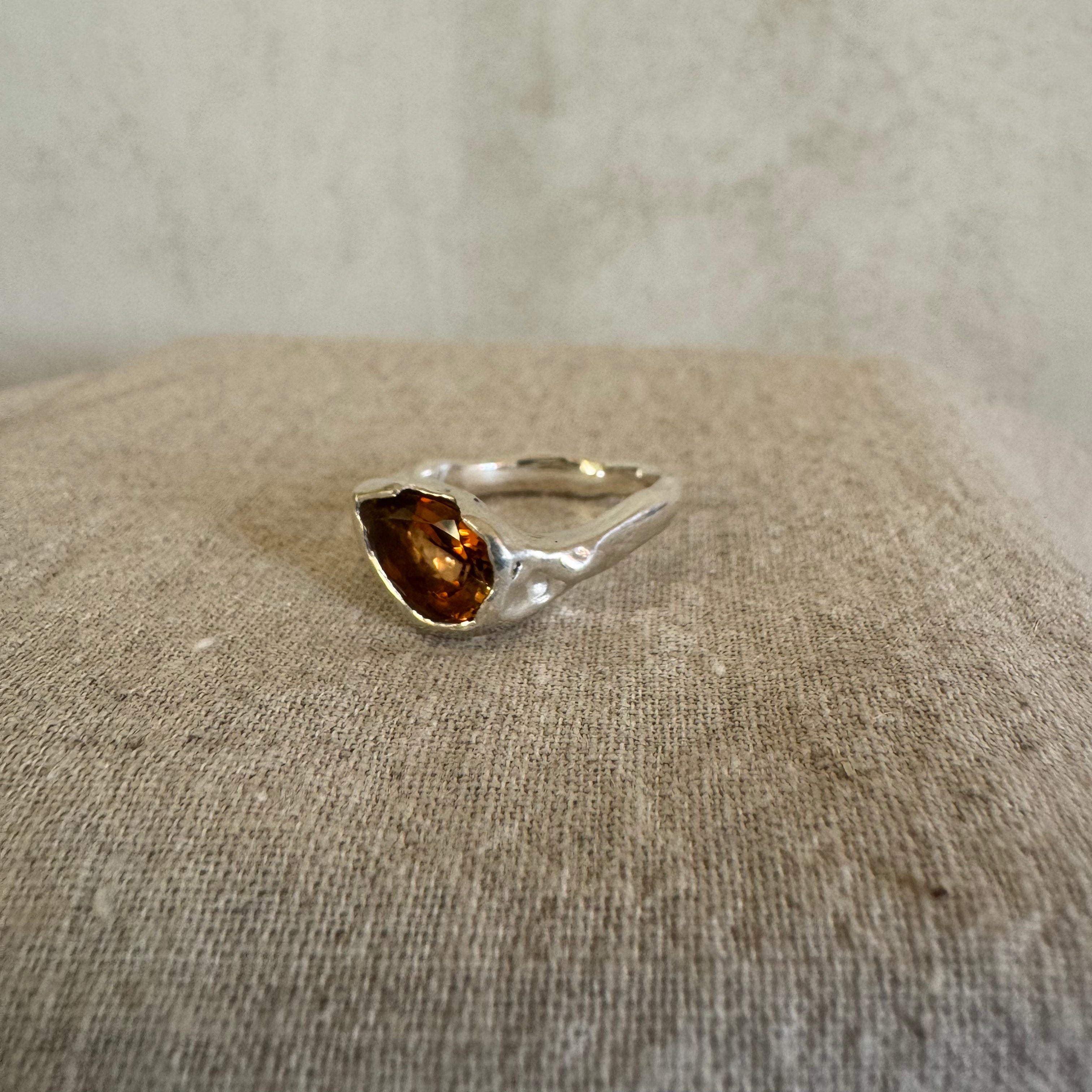 Silver ring with a amber tourmaline gemstone on a textured linen surface