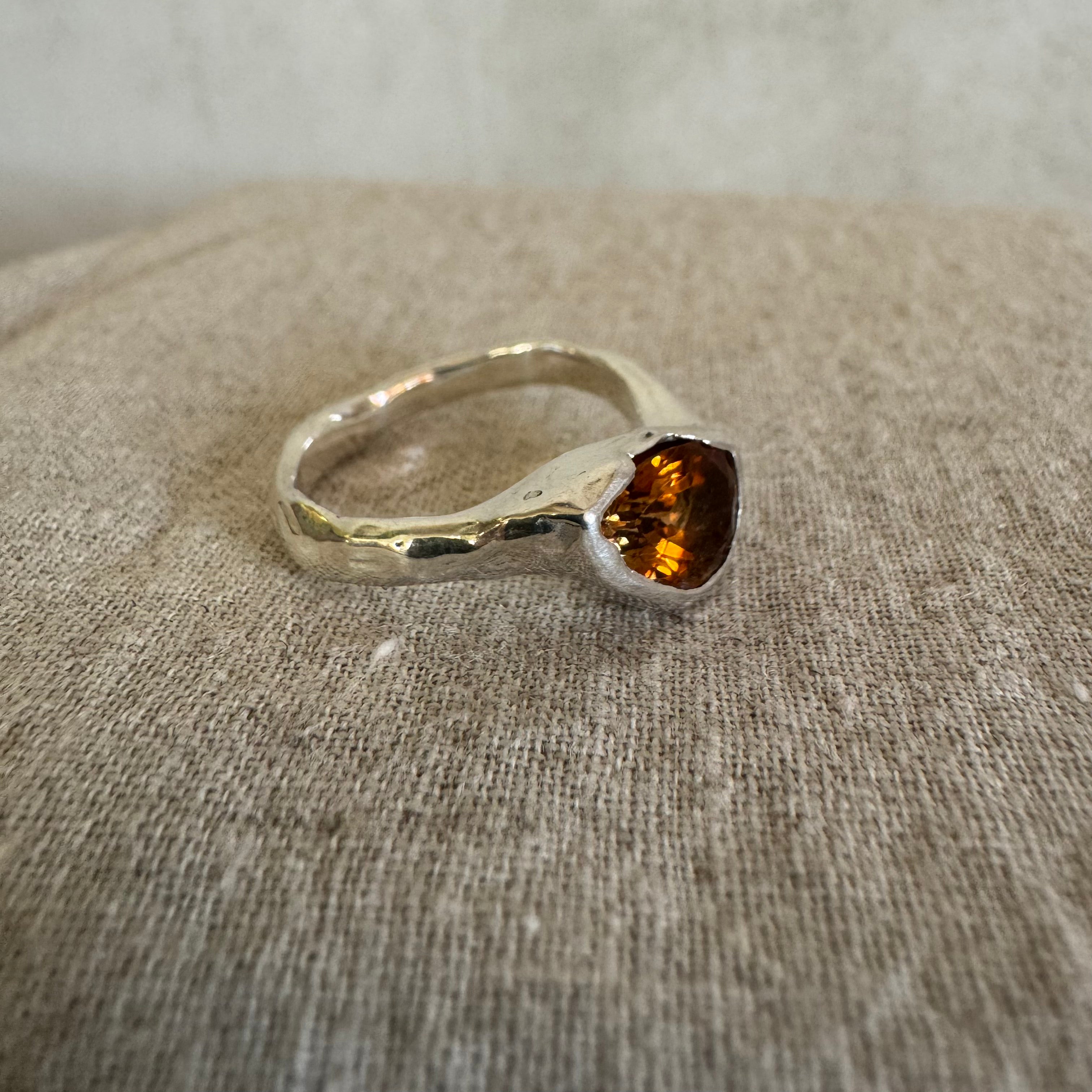 Organic Silver ring with a pear shaped amber tourmaline gemstone on a textured linen surface
