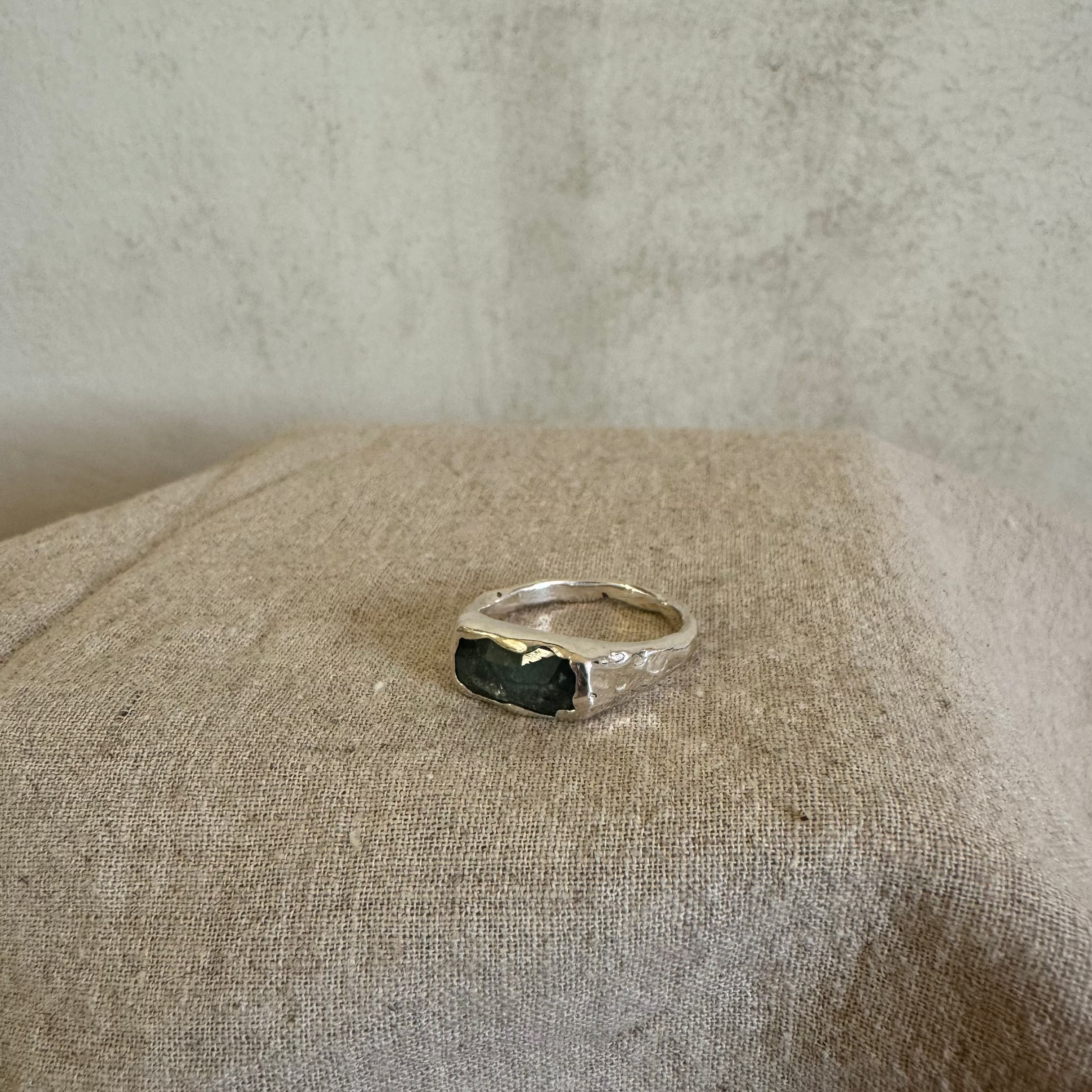 Silver ring with a blue kyanite stone on a textured beige surface